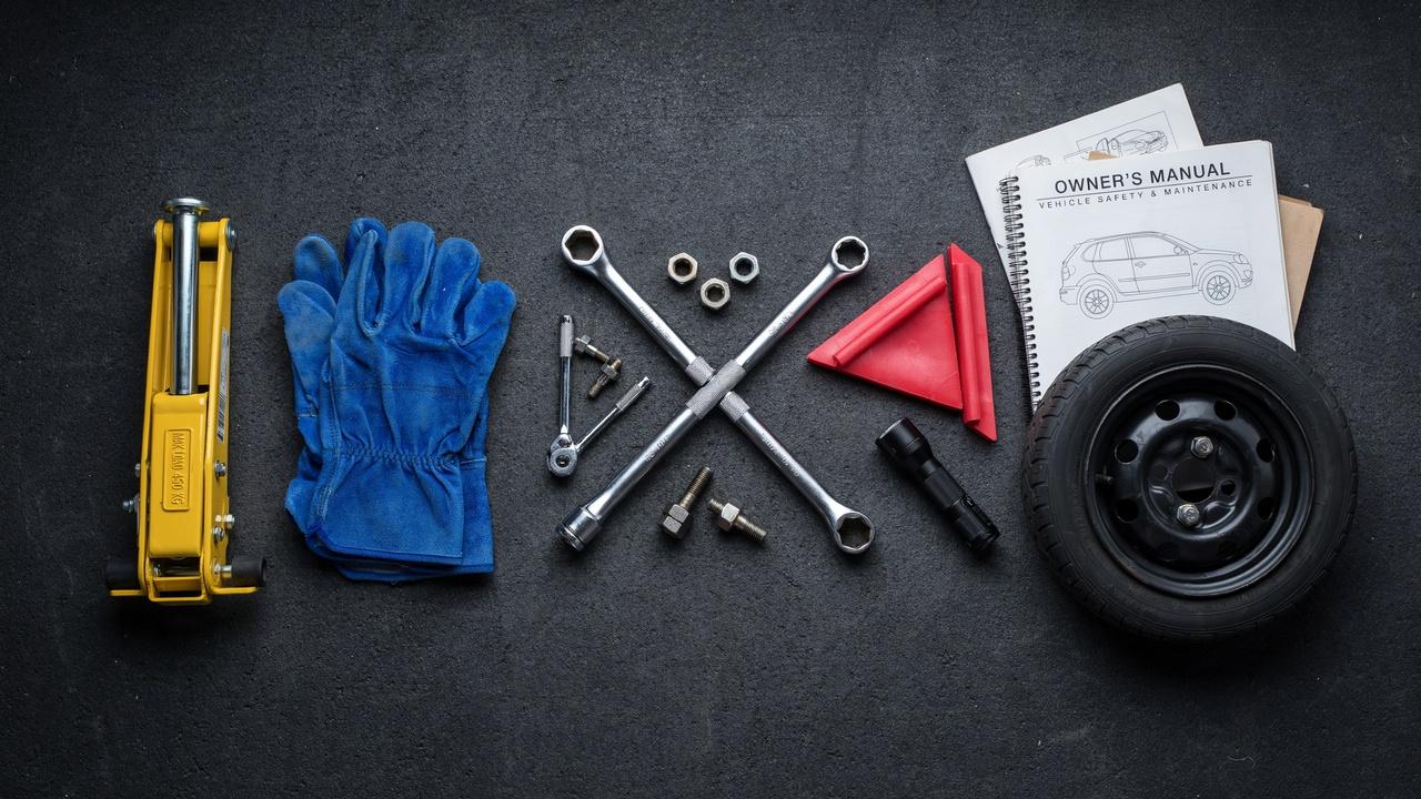 Essential tools needed before changing a car tire arranged neatly on the ground.