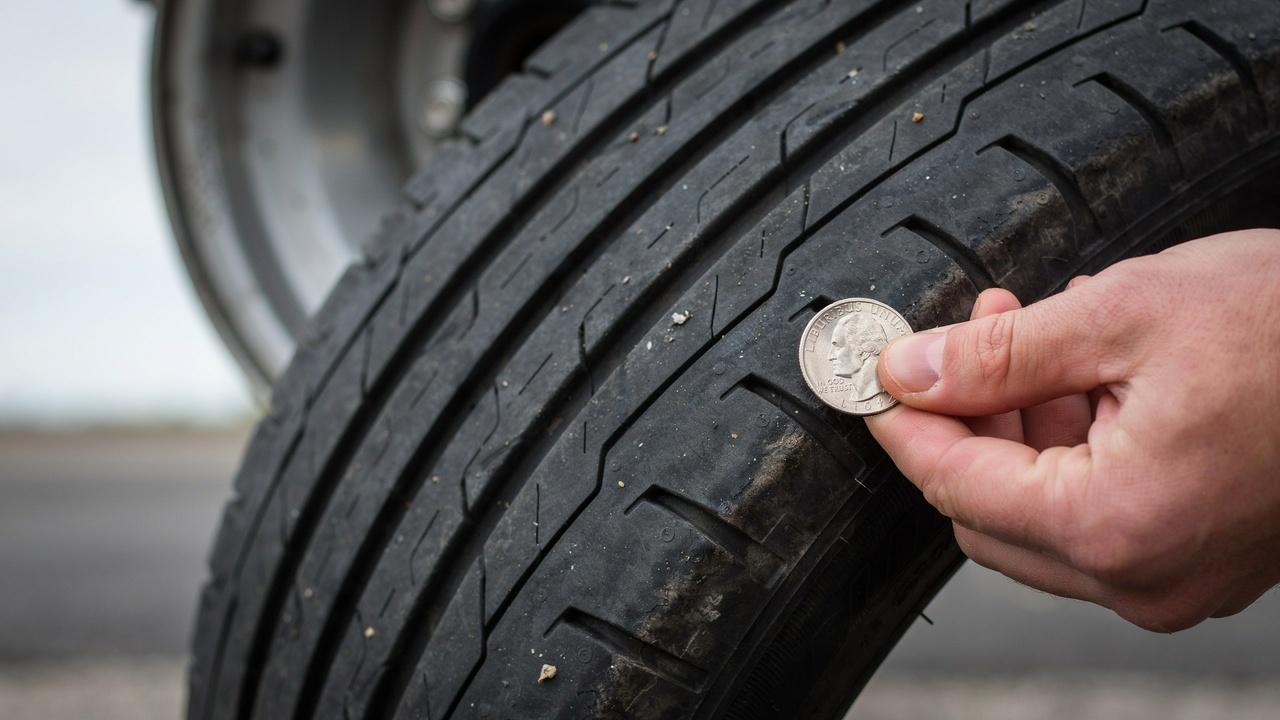 Using a nickel coin to check tire tread depth.