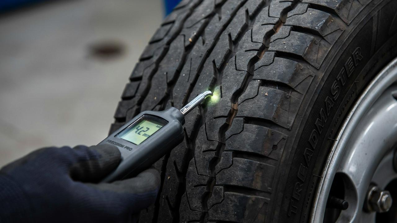 Digital tread depth gauge measuring tire tread.
