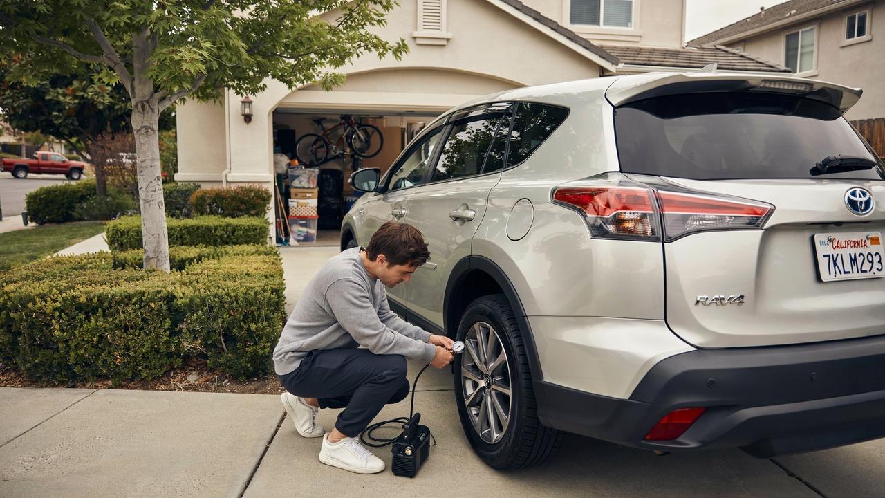 Driver performing quick tire pressure checks at home.