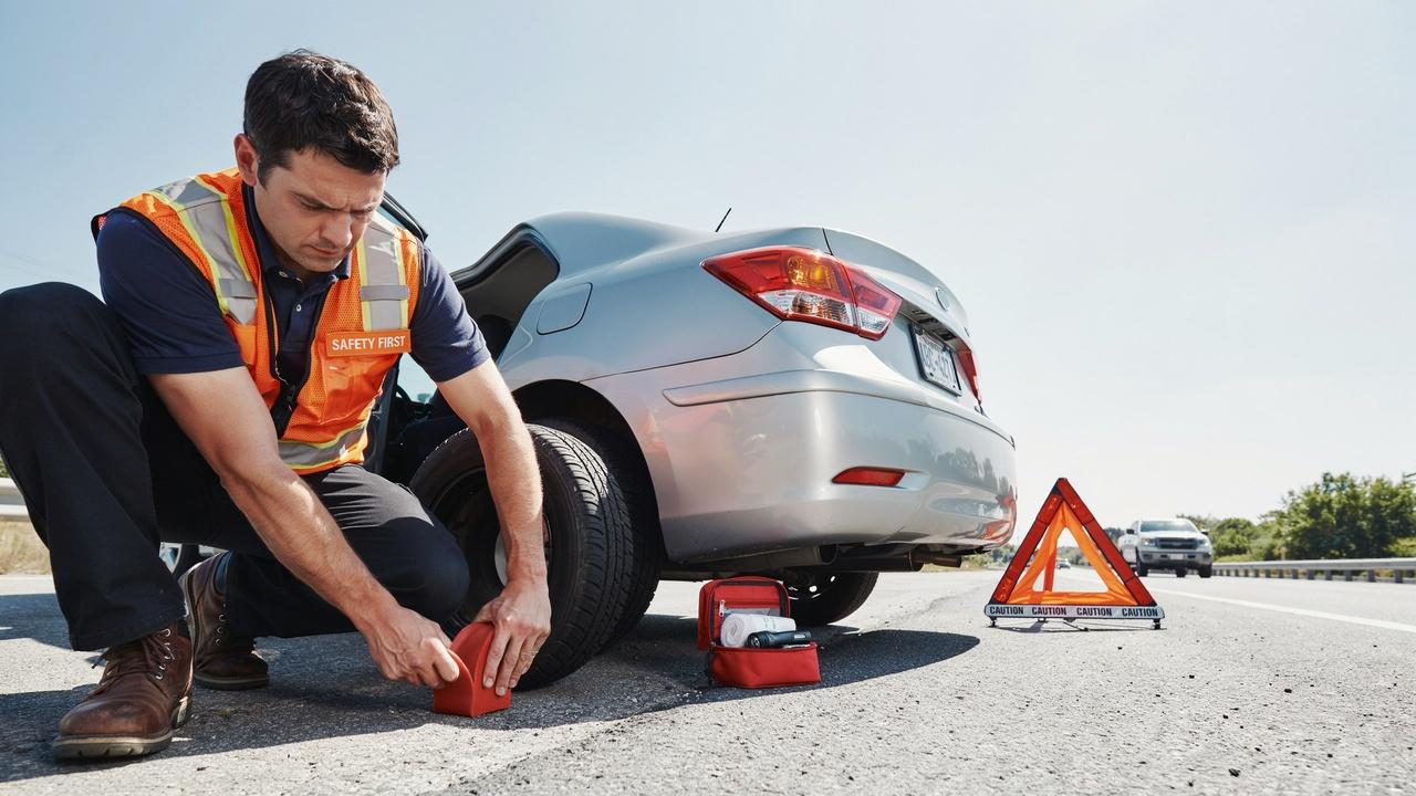 Safety steps before changing a tire including wheel wedges and hazard lights.