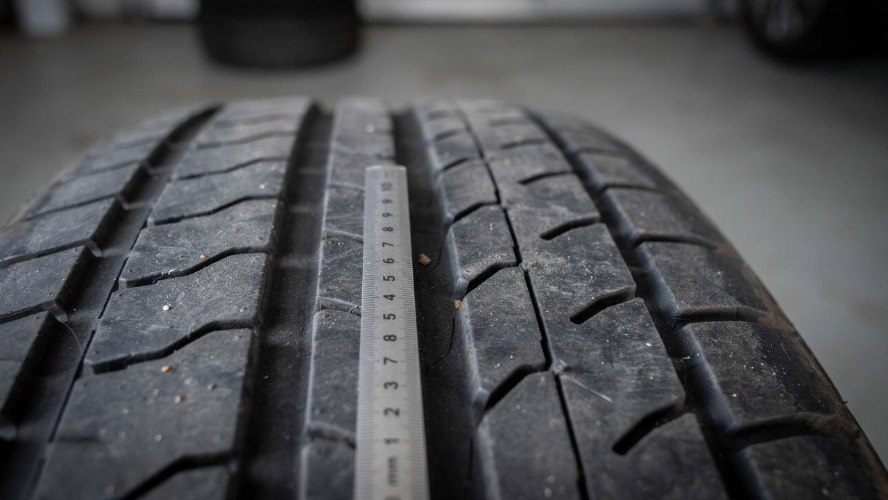 Measuring tire tread depth with a ruler.